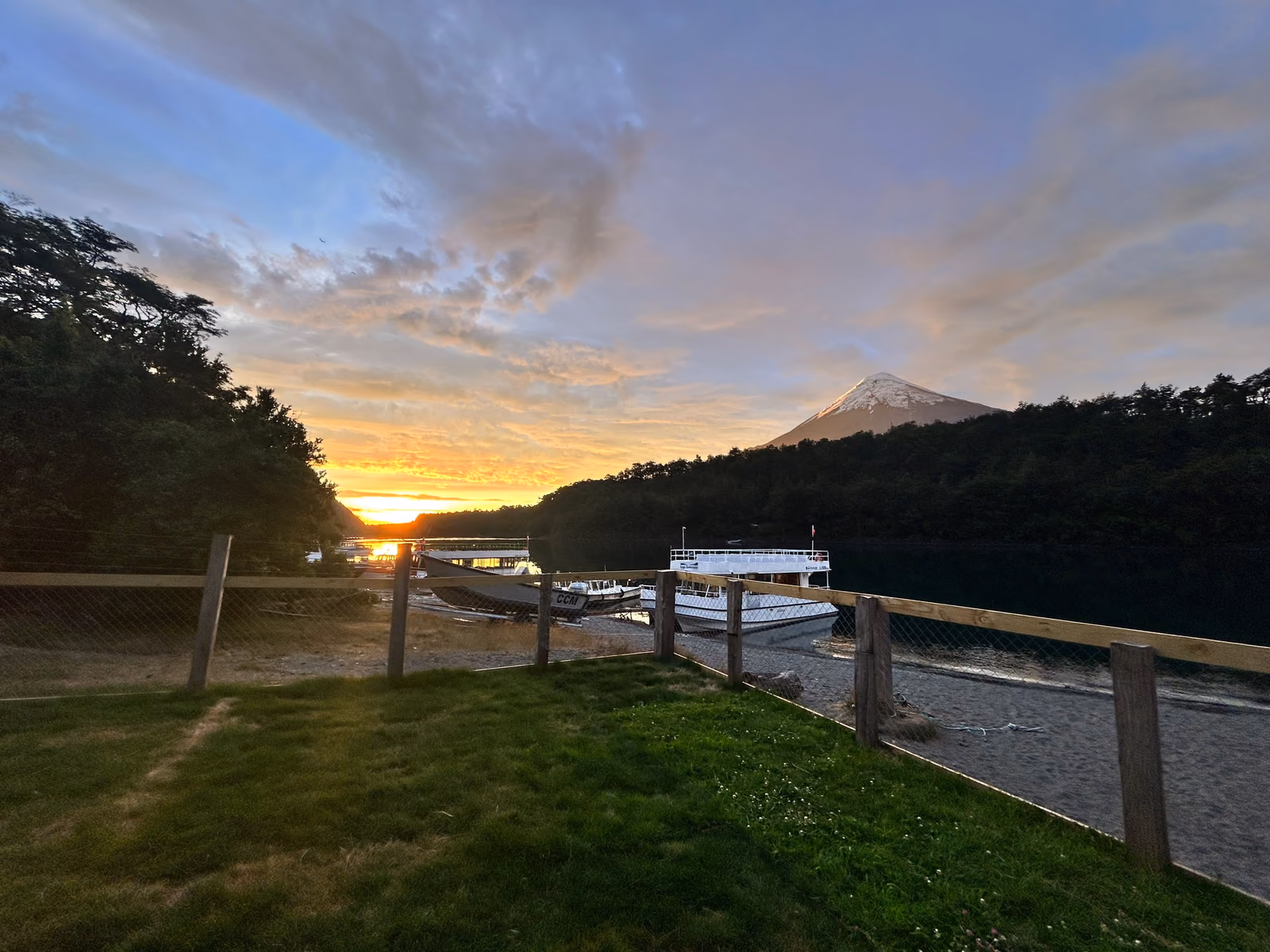 Atardecer desde el pasto del restaurante: lanchas en la playa, el lago y el volcán Osorno a la derecha.